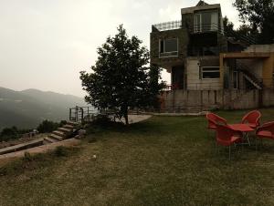 a house with chairs and a table in the grass at Luxe Villa in Murree
