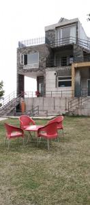 three red benches in front of a house at Luxe Villa in Murree