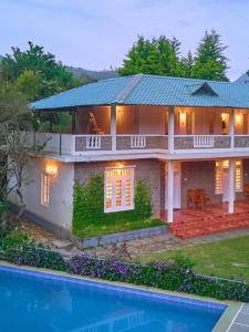 une grande maison avec une piscine devant dans l'établissement Ministers Mansion Kanthalloor Pool Resort by VOYE HOMES, à Kanthalloor