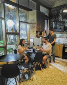 un groupe de personnes assises à une table dans une cuisine dans l'établissement Escarabajo Hostel, à Valparaíso