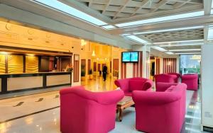 a large room with pink chairs and a television at Danau Toba Hotel International in Medan