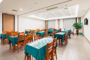une salle à manger avec des tables vertes et des chaises en bois dans l'établissement GreenTree Inn Jiangsu Wuxi Meiyuan Kaiyuan Temple Subway Master Station Express Hotel, à Wuxi
