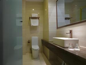 une salle de bain avec un lavabo, des toilettes et un miroir dans l'établissement Biway Fashion Hotel - Puyang Huanghe Road, à Zhongyuanyoutian 7 autres photos