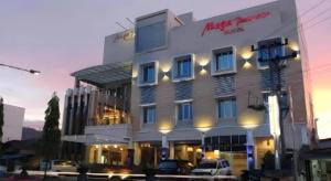 PadangsidimpuanにあるMega Permata Hotelの大きな白い建物とその前に駐車された車