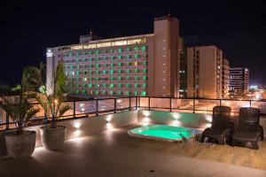 uma piscina no telhado de um hotel à noite em Amenit Hotel em Maceió
