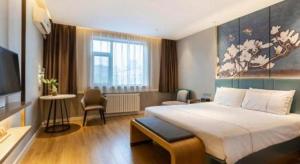 a hotel room with a large bed and a television at Magnotel Business Jining Huancheng North Road in Jining