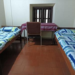 a room with two beds and a table and a chair at KOKDEERI NATURE HOME in Malappuram