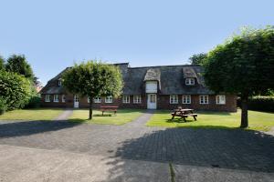 a house with a picnic table and benches in front of it at Friesisches Reetdachferienhaus in Bordelum