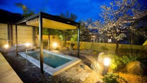 a swimming pool with a pavilion in a yard at night at Takato Sakura Hotel in Ina +45 photos