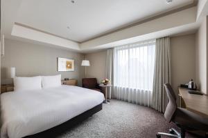 a hotel room with a bed and a desk and a window at Hotel Nikko Fukuoka in Fukuoka
