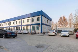 済南市にある7 Days Premium Jinan Gaoxin Qu Wanda Plazaの駐車場に車が駐車されている大きな建物