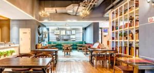 鄭州市にあるJames Joyce Coffetel Zhengzhou Aquarium Chenyan Flowerの木製テーブルと緑のソファのあるレストラン