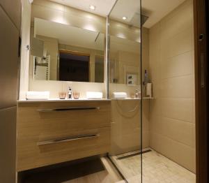 a bathroom with a sink, mirror, and bathtub at Hotel Edelweiss in Courchevel