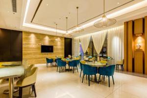 une salle à manger avec des tables, des chaises et une télévision dans l'établissement Jinjiang Inn Select Xixian New Distict Century Avenue, à Xianyang