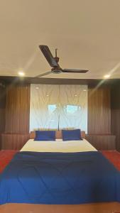 a bedroom with a large blue bed with a ceiling at Kings Court Village Resort in Araku