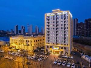 un grand bâtiment avec des voitures garées dans un parking dans l'établissement Jinjiang Inn Select Changchun Yuanda Street, à Changchun