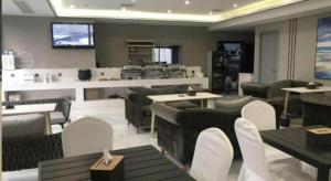 a restaurant with tables and chairs and a kitchen at Xana Hotelle·Hotel Luzhou Baizitu Square in Luzhou