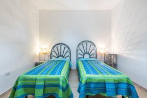 two beds in a room with blue and green sheets at Sottotorre 1 in Calasetta