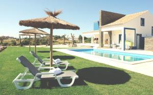 un grupo de sillas y sombrillas junto a una piscina en Casas Novas da Fataca, en Zambujeira do Mar