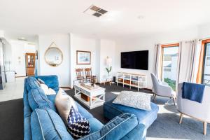 BaeView - Panoramic Group Stay Above Encounter Bay في Encounter Bay: غرفة معيشة مع أريكة وكراسي زرقاء