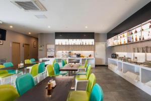 a restaurant with tables and green chairs and a counter at Echarm Hotel 1st Affiliated Hospital of Suzhou University Pingjiang in Suzhou