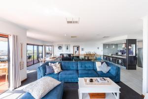 BaeView - Panoramic Group Stay Above Encounter Bay في Encounter Bay: غرفة معيشة مع أريكة زرقاء وطاولة