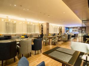 a restaurant with tables and chairs in a room at Echarm Hotel Wuhan Hankou Station Changgang Road Metro Station in Wuhan