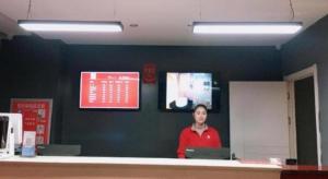 Un homme debout derrière un comptoir dans une pièce dans l'établissement Thank Inn Hotel Jiangsu Huaian Lianshui Baiyue Square, à Paifang