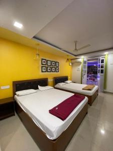 two beds in a room with yellow walls at Hotel sai advika in Guirim