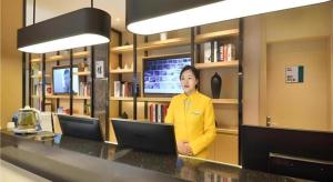 une femme debout à un bureau dans une bibliothèque dans l'établissement City Comfort Inn Wuhan Xinzhou Mo'er Cheng, à Wuhan