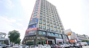 City Comfort Inn Dongguan Tangxia Garden Street في دونغقوان: مبنى مرتفع مع سيارات متوقفة أمامه