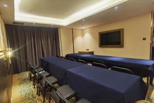 ein Konferenzraum mit blauen Tischen und Stühlen und einem Fernseher in der Unterkunft James Joyce Coffetel Changchun People's Square in Changchun