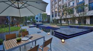 a patio with a table and an umbrella and benches at Zhejiang Cloud Mountain Deefly Hotel in Penshan