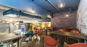 un restaurant avec des tables et des chaises et un mur de briques dans l'établissement James Joyce Coffetel Tianjin Railway Station, à Tianjin