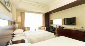 une chambre d'hôtel avec deux lits et une télévision à écran plat dans l'établissement Ramada Plaza by Wyndham Lianyungang, à Haizhou