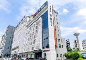 a large white building with cars parked in a parking lot at Borrman Hotel Dongguan Dongcheng Wanda Plaza Tianbao Metro Station in Dongguan