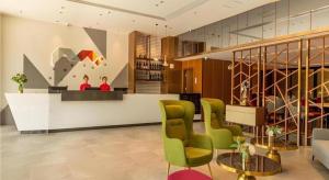 a lobby with green chairs and a reception counter at Borrman Hotel Dongguan Dongcheng Wanda Plaza Tianbao Metro Station in Dongguan