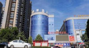 SuiにあるXana Lite Shangqiu Sui County Dennisの青い建物の前に停車する車