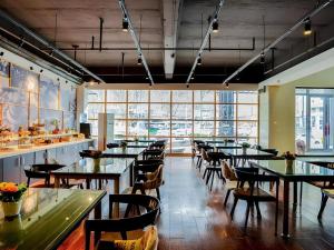 une salle à manger avec tables, chaises et fenêtres dans l'établissement Urban Garden Hotel Chengyang District Government Liuting Airport, à Qingdao