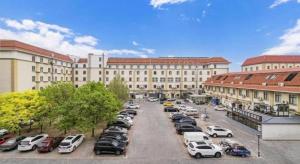 a large building with cars parked in a parking lot at Xana Lite Hotelle Tianjin Huaming Binhai International Airport in Tianjin