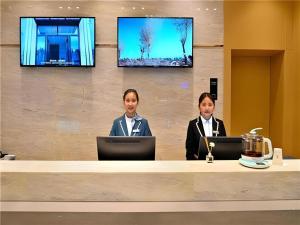 City Comfort Inn Kunming High Speed Railway South Station Yongxin Harvard في كونمينغ: كانتا جالستين في مكتب مع أجهزة اللاپتوپ الخاصة بهن