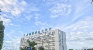 un bâtiment blanc avec une enseigne au sommet dans l'établissement GreenTree Inn Express Guangxi Nanning Mingyang Avenue Nanning Airport, à Nanning