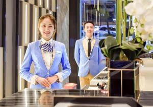 a man and a woman wearing suits in a room at Echarm Hotel Guiyang North High-speed Railway Station in Guiyang