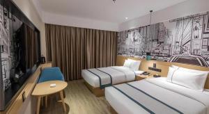 une chambre d'hôtel avec deux lits et une télévision dans l'établissement City Comfort Inn Loudi Sports Center, à Loudi