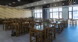 un restaurant avec des tables et des chaises en bois et des fenêtres dans l'établissement Green Tree Inn Fengxian New City Metro Station Jiukeshu Art Center, à Sanguantang