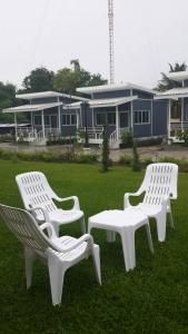 three white chairs sitting in the grass in front of a house at Sweet Infinity @332 in Bang Sare