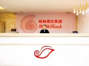 un homme se tient devant un mur avec un panneau dans l'établissement Shell Hotel Shanghai Expo Changqing Road Metro Station, à Shanghai