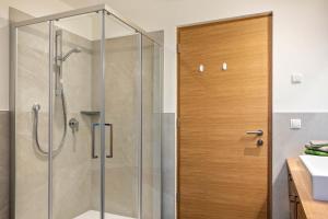 une douche avec une porte vitrée dans une salle de bain dans l'établissement Mittnackerhof Apartment Ringelblume, à Sarentino 13 autres photos