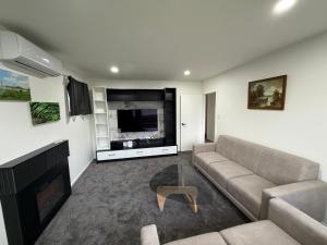 a living room with a couch and a flat screen tv at Gee's House in Upper Hutt