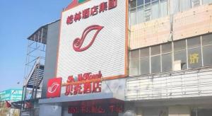 a building with a sign on the side of it at Shell Hotel Liaocheng Dongchang Xi Road Railway Station in Liaocheng